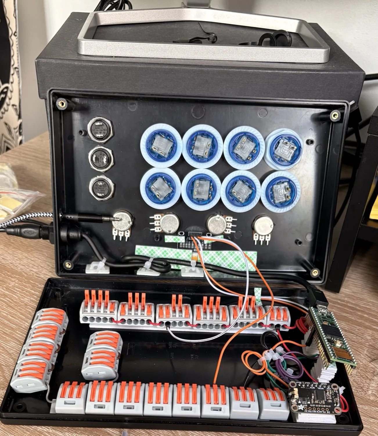 The drum machine open on a desk mid-assembly — eight arcade pads and four pots mounted in the drilled lid, with the Teensy, DAC and rows of lever connectors filling the base